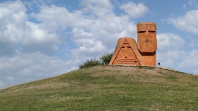 En skulptur föreställande en stiliserad man och kvinna uppe på en kulle.