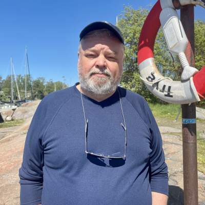 En man vid namn Juha Flinkman står på en strand med en blå tröja på sig.