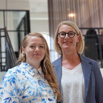 Lærke Søndergaard Kristensen och Anne Merrild. Två välklädda kvinnor i en modern kontorsmiljö. Kontoret är i toppskick.