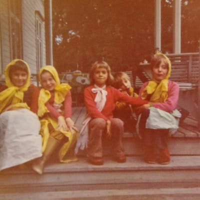 Fem barn sitter på en trappa. Fyra har gula dukar på huvudet. Fotot äör taget på 1970-talet.