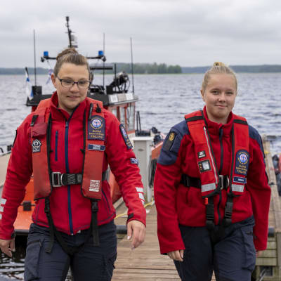 Två personer på en brygga med två båtar i bakgrunden.