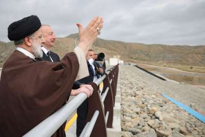 Irans president Ebrahim Raisi står vid ett staket. Bredvid honom står Azerbajdzjan president Ilham Alijev.