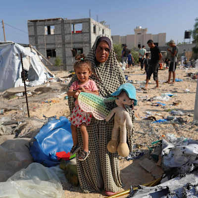 Palestinsk kvinna håller ett barn och en docka i famnen.