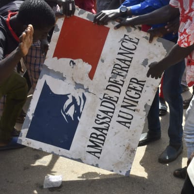 Demonstranter håller i en skylt från franska ambassaden i Niamey.