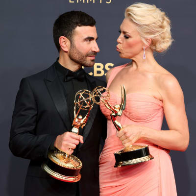 Brett Goldstein och Hannah Waddingham poserar tillsammans med sina Emmystatyetter. Brett bär en svart kostym, medan Hannah bär en rosa långklänning.