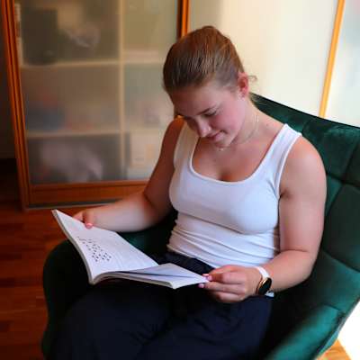 Emilia Sundström läser en gymnasiebok i en fåtölj.