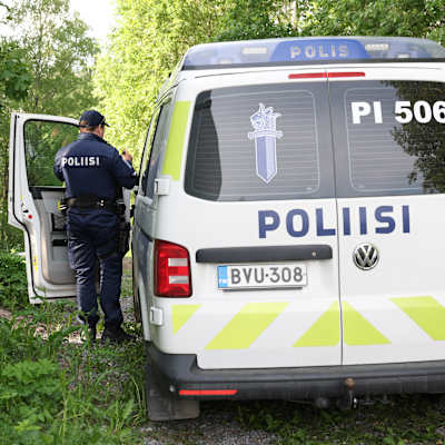 polis står bredvid en polisbil i en skog.