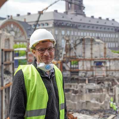 Lars Daugaard Jepsen vid Dansk Erhverv. I bakgrunden syns ruinerna från Börsen som brann i Köpenhamn den 16 april.