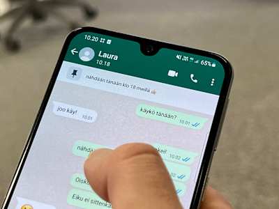 En telefonskärm med en Whatsappkonversation. På skärmen är en tumme. Samtalet är på finska och där kommer man överens om att ses samma kväll klockan 18.
