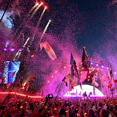 Fyrverkerier, flaggor och konsertbesökare framför scen på Coldplays spelning på Glastonburyfestivalen. 