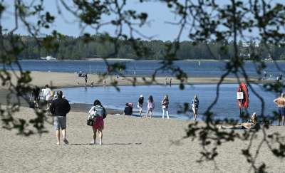 Personer går på en strand under en solig dag.