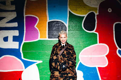 Annu Kemppainen, verksamhetsledare för Helsingfors Pride, står framför en färggrann vägg.