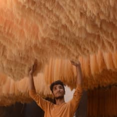 Mies tarkistaa Itä-Pakistanilaisessa tehtaassa nuudelien kuivumista Lahoressa.