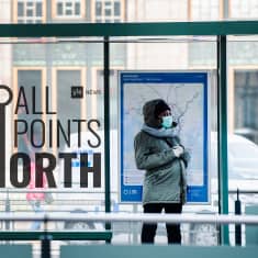 Photo of woman waiting at bus stop in Helsinki featuring All Points North podcast logo.