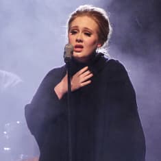 Adele laulaa lavalla, sinisen hämyn takaa näkyy rumpali.