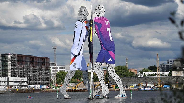 Die Skulptur "Molecule Man" in Berlin trägt die verschiedenen Trikots der deutschen Fußball-Nationalmannschaft.