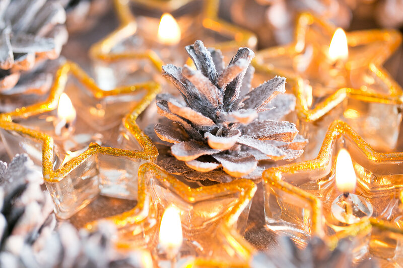 Christmas. Christmas card with glowing small candle and fir cones on old wooden background.