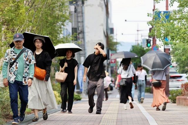 日傘を手に歩く通行人。年間最多日数となった高梁市など岡山県内各地で猛暑日を観測した＝８日午後２時１２分、岡山市中心部