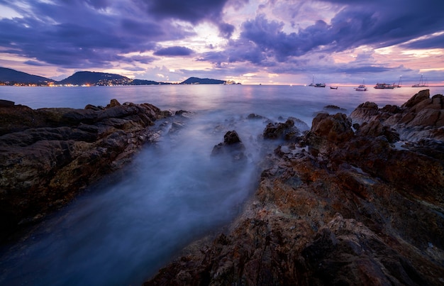 Long exposure image of Dramatic sky seascape with rock in sunset scenery