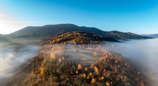 Thick fog among peaks of high autumn mountains at sunrise