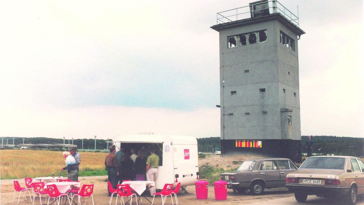 Ein Beispiel für eine originelle Umnutzung, wie sie auch in der virtuellen Ausstellung zu sehen ist. Der Besitzer eines mobilen Kiosks hat Stühle und Tische aufgebaut, der Grenzstreifen ist kurz nach der Grenzöffnung zum Ausflugsziel geworden. Im Hintergrund ist die ehemalige Grenzübergangsstelle Marienborn zu sehen (Archivfoto).