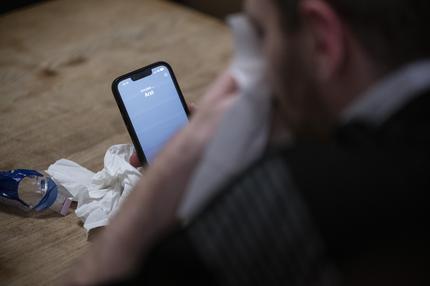 Kassenärztliche Bundesvereinigung: Ein Mann hält ein Taschentuch in einer Hand und ein Telefon mit dem Schriftzug "Arzt" in der anderen.