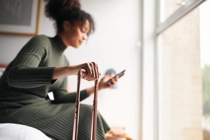 Buchungsportal: Woman with suitcase checking out of boutique hotel sitting on bed waiting for taxi ordered on mobile phone app, Woman With Suitcase Checking Out Of Boutique Hotel Waiting For Taxi Ordered On Mobile Phone App model released