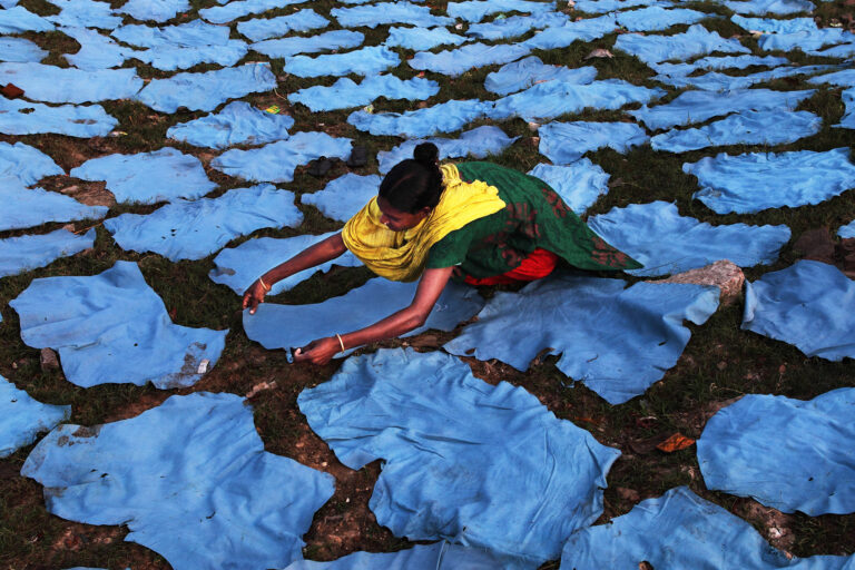 A woman is laying leather out to dry in Bangladesh.