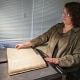 Photograph of Abigail Guidry using the book scanner to digitize a bound volume at the Library Company