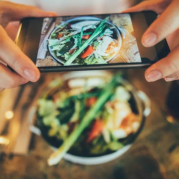 A business owner taking a picture of their salad to upload to social media