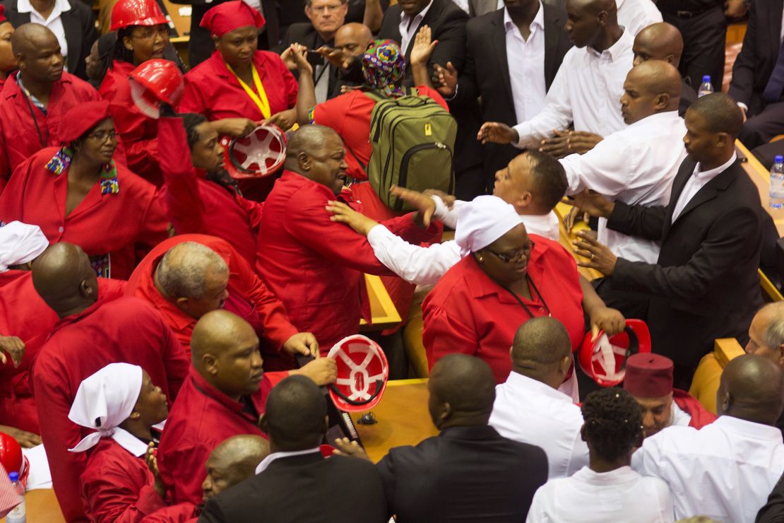 Members of the Economic Freedom Fighters, wearing red uniforms, clash with security forces during the South African President's State of the Nation address in Cape Town on February 12, 2015. 