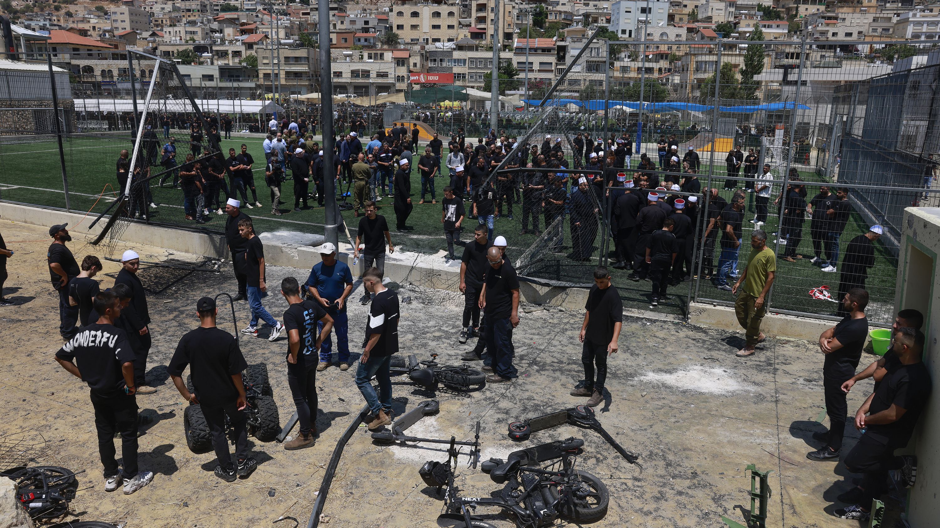 Members of the Druze community in Majdal Shams look at the damage from a rocket strike at a football pitch that killed 12 people in the Israel-annexed Golan Heights, on July 28, 2024.