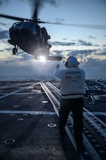 U.S. Navy Boatswain’s Mate 2nd Class John Delacuesta signals an approaching U.S. Army HH-60M Black Hawk helicopter, assigned to the “Hammerheads” of 3rd Battalion, 25th Aviation Regiment, as it prepares to land on the flight deck of the Arleigh Burke-class guided-missile destroyer USS Gridley (DDG 101) during Exercise Rim of the Pacific (RIMPAC) 2024, July 21.