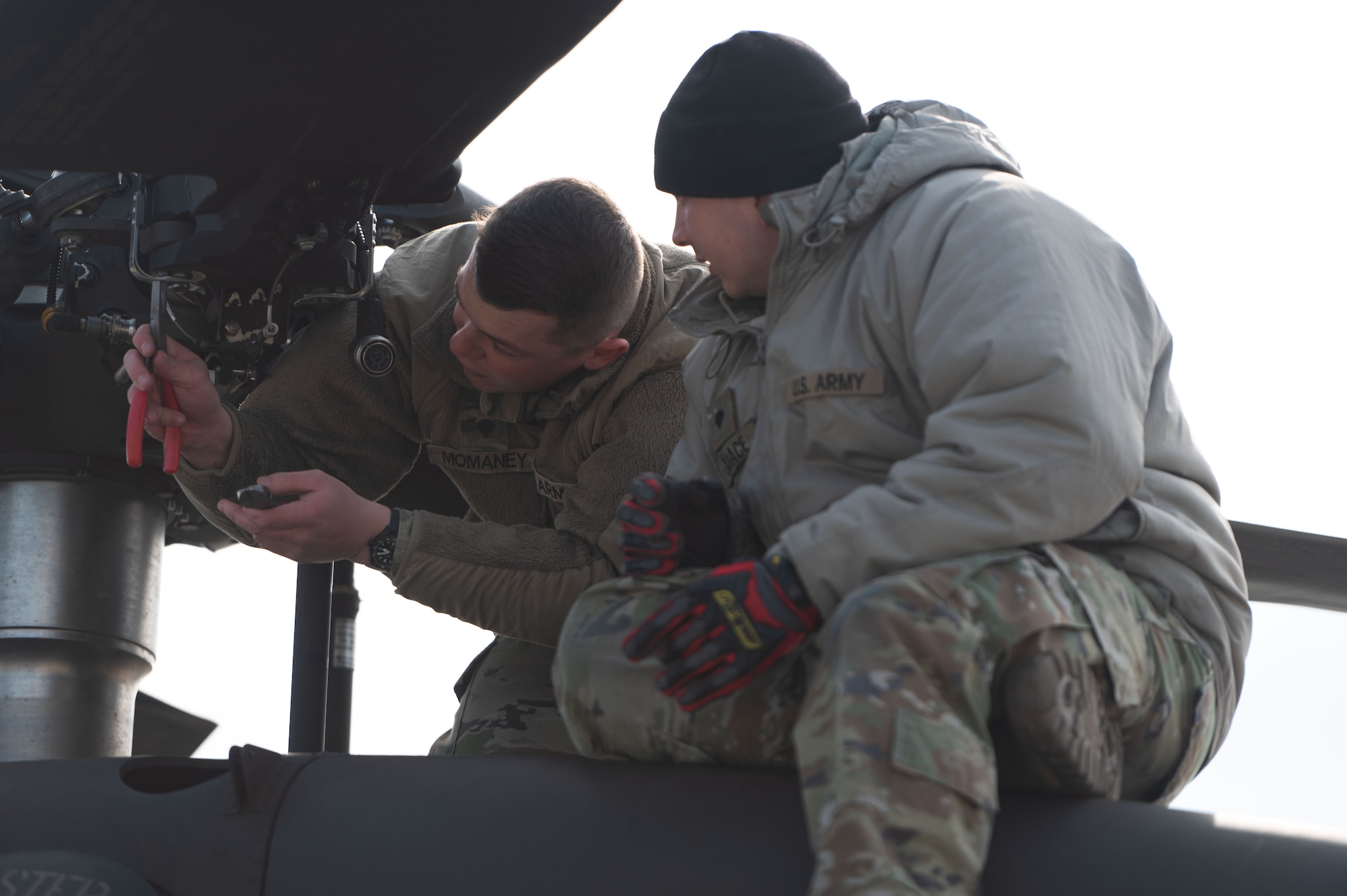 Spcs. Timothy Momaney and Cameron Lagace, mechanics with the 238th Medevac Company, begin the blade folding process on top of a HH-60M Black Hawk at Pease Air National Guard Base, New Hampshire, March 13, 2024. The team spent three days folding the aircraft blades, palletizing gear, completing a joint inspection and loading the equipment onto a C-17 for transport to Exercise Granite Falco in Cabo Verde.
