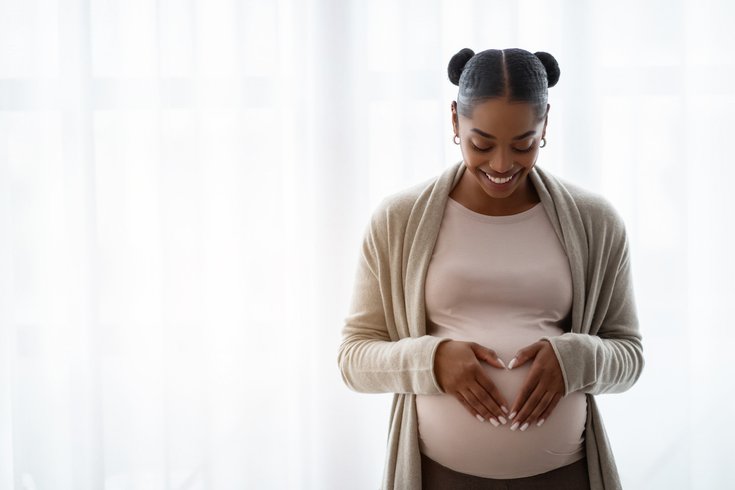 Purchased - Smiling pregnant woman holding hands on belly