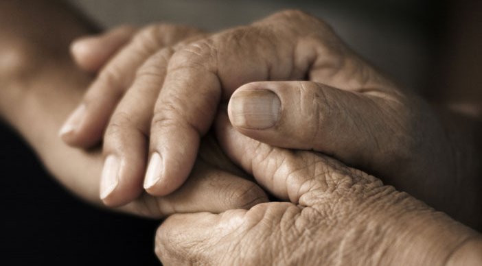 Close-up of a person's of hands clasped around another person's hands.