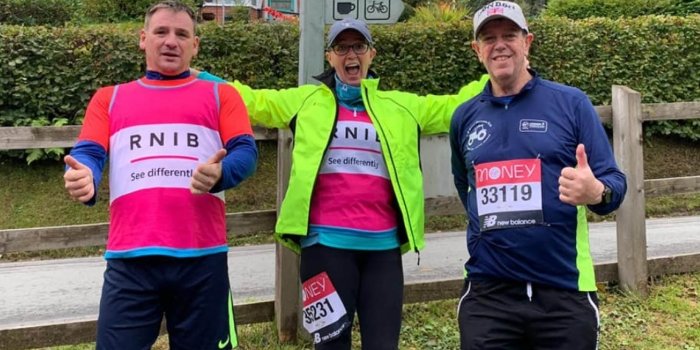 Three people wearing RNIB branded tshirts in pink and running labels.