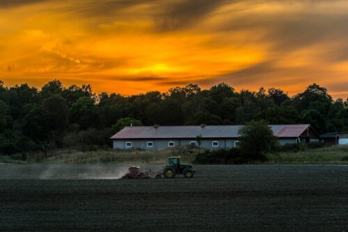 Traktor med såmaskin i solnedgången