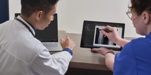 A male and female healthcare worker working on a laptop screen