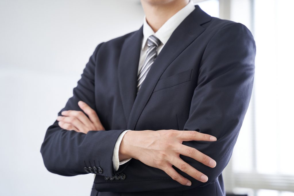 A Japanese male businessman folds his arms in a conference room