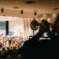 In the foreground, a musician plays the flugelhorn toward an orchestra onstage