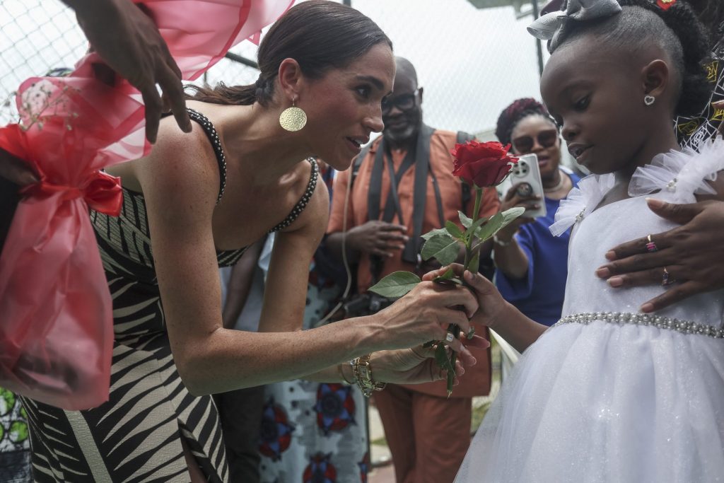 Meghan, Duchess of Sussex, receiving flowers from a girl at a sitting volleyball exhibition match in Abuja, Nigeria for the Invictus Games anniversary.