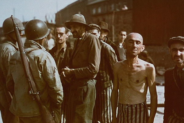 <p>American soldiers speak with a group of survivors while on a tour of the Buchenwald concentration camp on April 18, 1945. <i>National Archives and Records Administration</i></p>