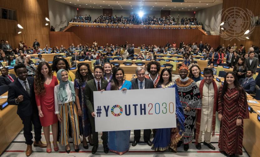 Secretary General António Guterres standing with youth participants at a high level event