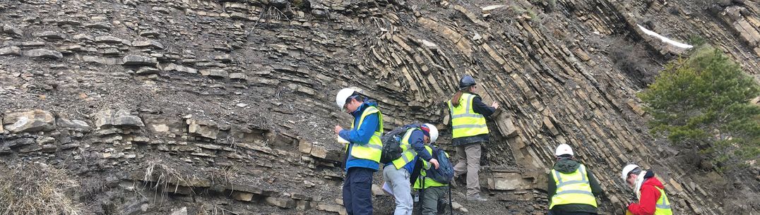 Students in high-vis and helmets look at structures and folds on Earth science fieldtrip