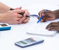 Close up of hands writing on a notepad