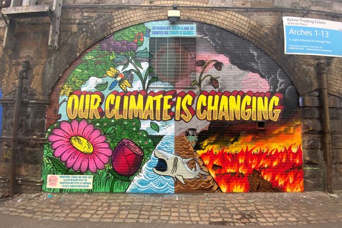 A railway arch painted with a colourful artwork with the words 