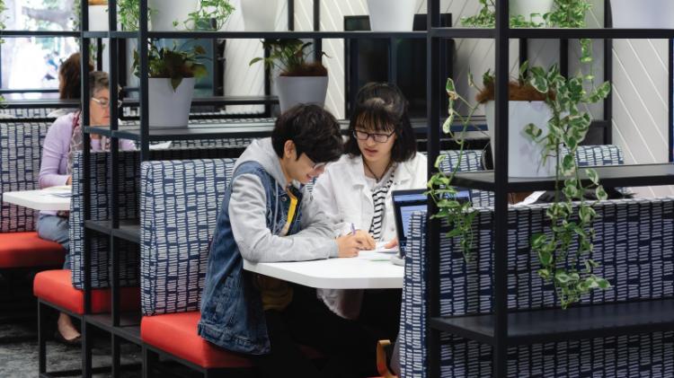 Students sitting at a group table in the refreshed space on the Ground Floor of UOW Library Wollongong Campus