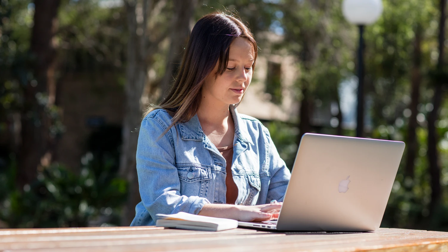 A person sitting outside at Wollongong Campus using a laptop