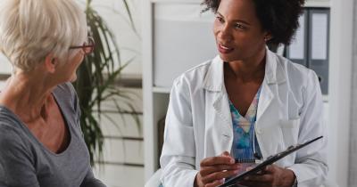 Woman holding clipboard speaking to another woman in a medical office